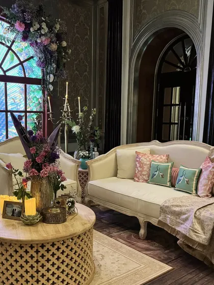 A vintage-style lounge area with plush seating, bird-print cushions, and dramatic floral arrangements, creating a sophisticated and comfortable space.