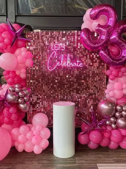 A glamorous "Let's Celebrate" 35th birthday. The pink sequin wall is the star of the show, framed by a stunning arrangement of hot pink and metallic balloons.