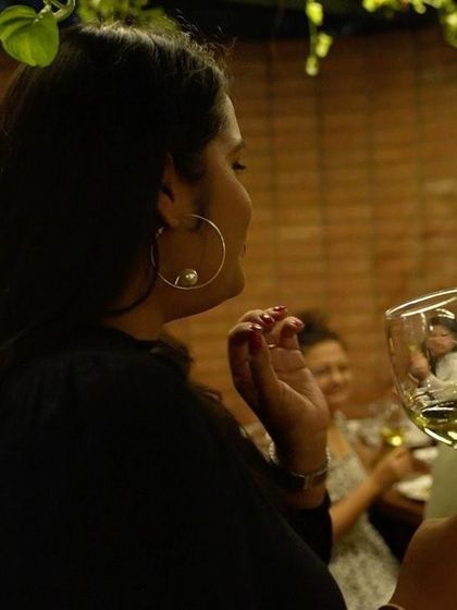 A guest admiring a glass of white wine, with her reflection captured in the glass.