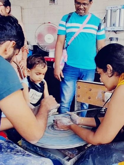 Even the littlest hands can create. Here, a young child experiences the magic of the pottery wheel with the help of an adult, his eyes full of curiosity.