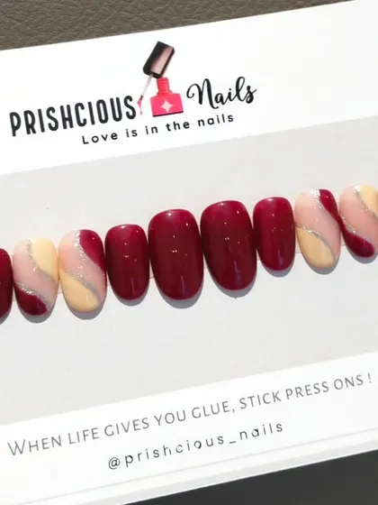A beautiful custom press-on set in a rich maroon, accented with nude nails and a delicate silver glitter swirl.
