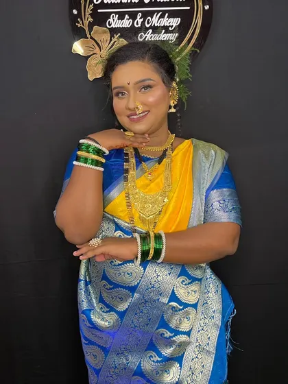 A graceful pose that highlights the beautiful contrast of the yellow and blue saree against her glowing skin.
