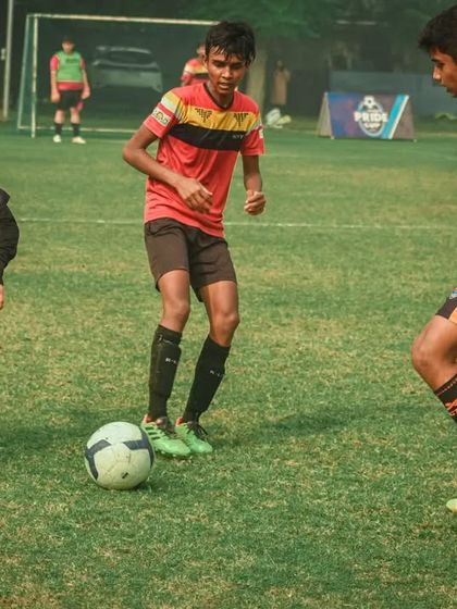 Three players are involved in a chase for the ball.