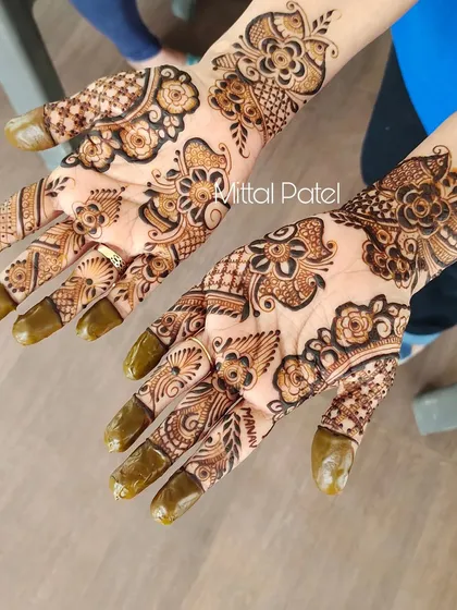 This design features a beautiful trail of flowers and leaves flowing diagonally across the hand. It's a graceful and feminine style that elongates the fingers.