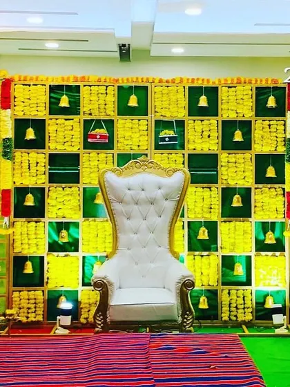 A wide view of a traditional backdrop made with betel leaves and marigolds, featuring hanging bells. This versatile design is perfect for engagements, naming ceremonies, or baby showers.