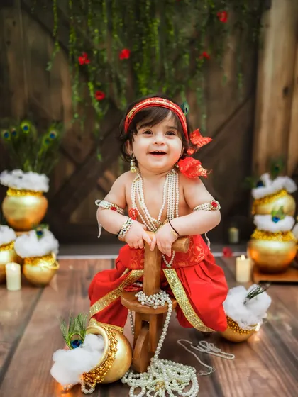 A radiant smile from our little Ladoogopal. He is the star of the show in this festive setup.