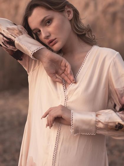 An intimate close-up focusing on the delicate lace trim on the V-neck and cuffs of the dress. This detail shot is crucial for communicating the quality and craftsmanship of the garment.