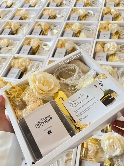A closer look at one of the Hajj & Umrah return gift boxes, showing the prayer mat, tasbeeh, and custom card.