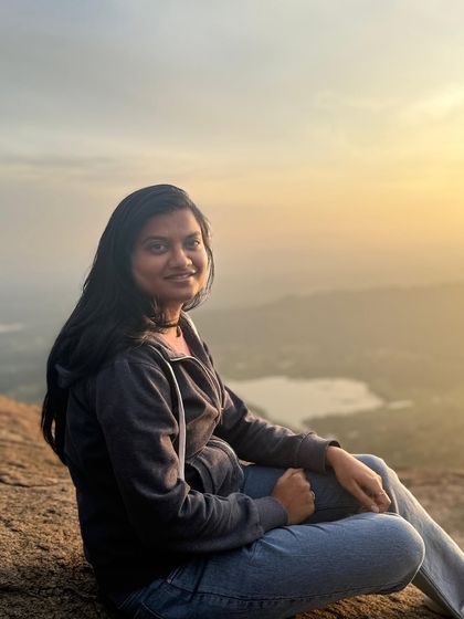 A smiling trekker poses for a photo, with the golden light of the sunrise creating a beautiful glow.