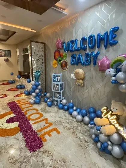 A wide-angle view of the "Welcome Baby" room decoration, showing the flower petal art on the floor and the full balloon setup.