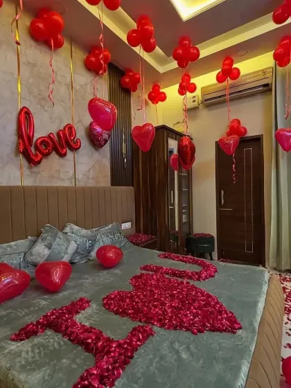 A close-up of the romantic bedroom setup, showing the detail of the rose petals on the bed and the heart-shaped foil balloons.