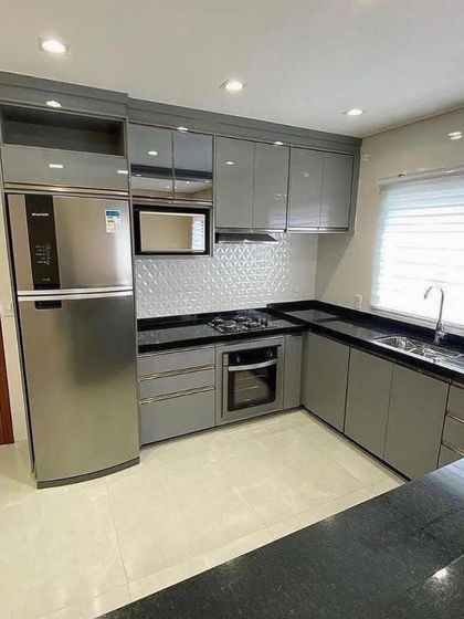 This image highlights the integration of the refrigerator and microwave within the glossy grey cabinetry, creating a seamless and organized kitchen design.