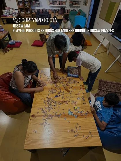 An overhead shot of a family working together on a large jigsaw puzzle at our Jigsaw Jam.