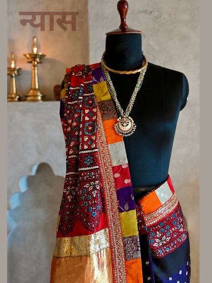 A detailed shot focusing on the pallu, where the vibrant red of the Ajrakh block-print and the multi-colored patchwork border truly shine. The layering of textures is central to my design philosophy.