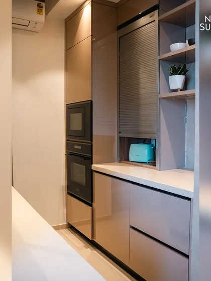 A look at the integrated appliance unit, which houses the oven and microwave in a sleek, vertical stack. This space-saving solution is paired with a roller shutter cabinet to neatly conceal smaller appliances, keeping the countertop clutter-free.