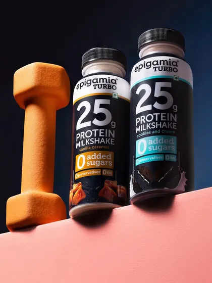 This shot for Epigamia's Turbo protein milkshake connects the product directly to fitness. Placing the bottles next to a dumbbell on a pink and blue background creates a modern, energetic image for a health conscious audience.