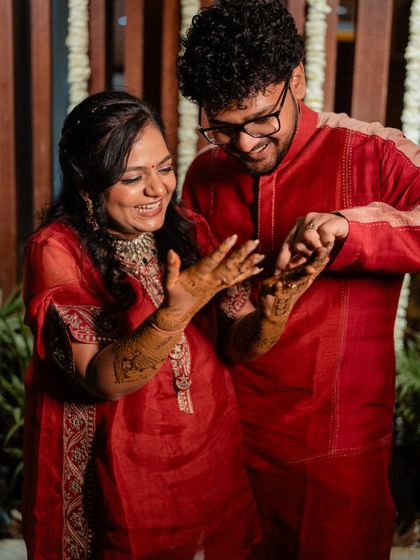 The bride and groom sharing a playful moment, checking out their intricate mehendi designs.