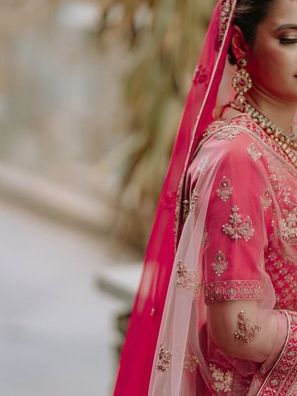 A side profile of the bride, highlighting the details of her makeup, jewelry, and the embroidery on her blouse.