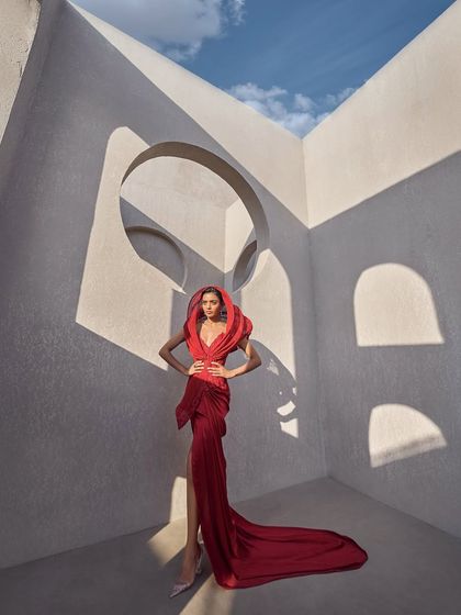 A structured red hooded gown designed for bold elegance. The tailored silhouette hugs the body, while the architectural hood frames the face, merging contemporary structure with classic glamour.