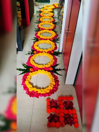 A beautiful floral runner for a hallway. This design consists of repeating circles made from yellow and pink rose petals, with a sacred Swastika symbol made of marigold petals at the end.