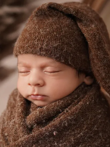 A close-up of the sleeping baby from our cozy camping theme. The soft, textured wrap and knitted hat keep him warm and secure, highlighting his peaceful expression.