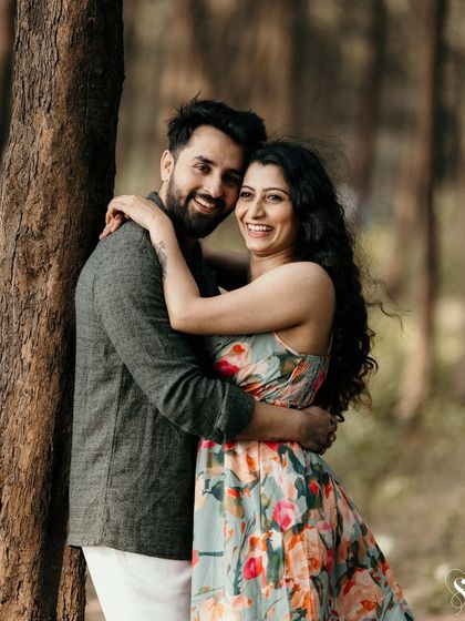 A happy embrace amidst the trees. The natural forest setting provides a beautiful, serene backdrop for this couple's joyful and candid pre-wedding portrait.