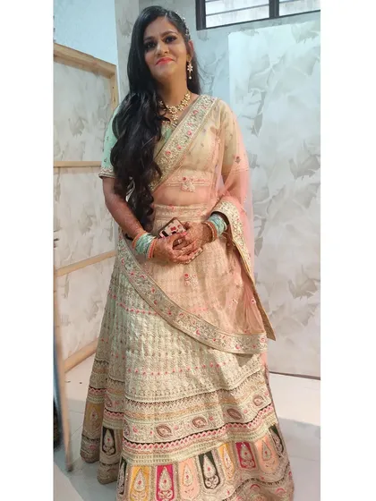 A client trying on a beautiful pastel lehenga with colorful border details in the studio. This is a great option for a day wedding or engagement.