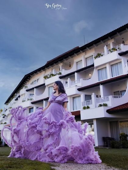 A wide shot showcasing the grandeur of the gown against the resort architecture. The long, ruffled train makes a statement and is perfect for creating epic, scenic photos.