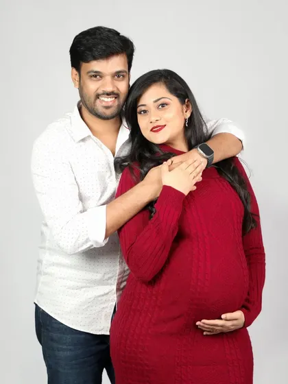 Simple, sweet, and full of love. This couple's studio portrait in a cozy red sweater dress perfectly captures the warmth and happiness of expecting a child.