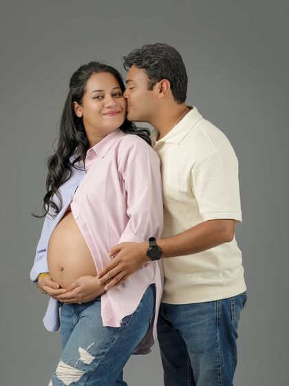 A gentle kiss for the mom-to-be. This casual, jeans-and-shirt look shows off the baby bump beautifully and captures a moment of pure affection.