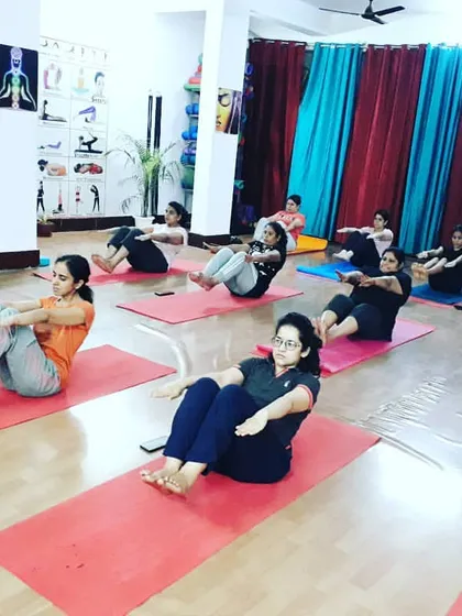 The class engages their core muscles in Ardha Navasana (Half Boat Pose). Building a strong core is fundamental for stability in all other yoga postures and for protecting the lower back.