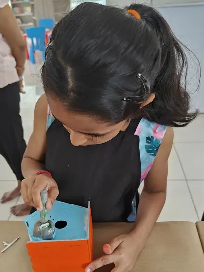 A young artist carefully paints the inside of her birdhouse. We love seeing the concentration and care they put into their work.