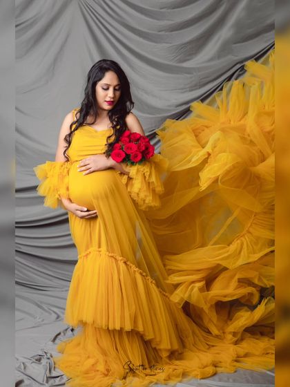 Holding a bouquet of red roses, the mom-to-be in the yellow gown creates a beautiful color contrast in this elegant maternity photo.