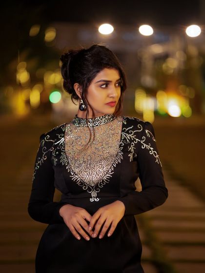 A close-up of actress Sanjanaa Anand from an evening shoot, with beautiful bokeh from the city lights in the background.