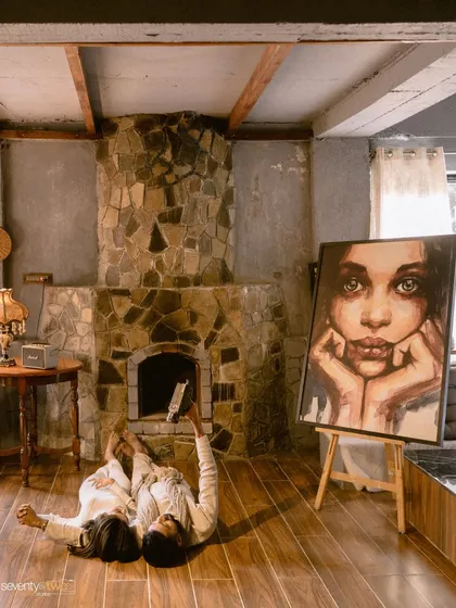 A playful and unconventional portrait. Lying on the floor by the fireplace, he films her, turning the idea of a pre-wedding shoot on its head. It’s about their story, their way.
