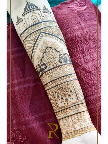 This bridal arm design features classic Rajasthani architectural elements, with elephants in the jharokhas and intricate geometric patterns.