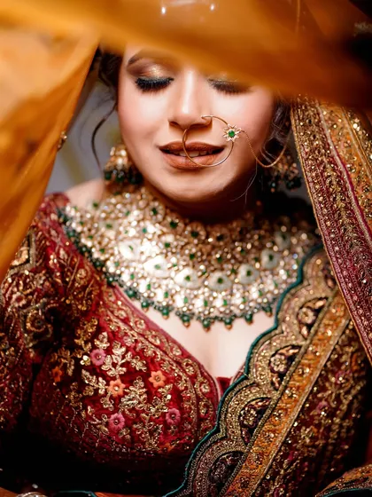 A close-up bridal portrait, focusing on her serene expression and the stunning details of her necklace and veil.