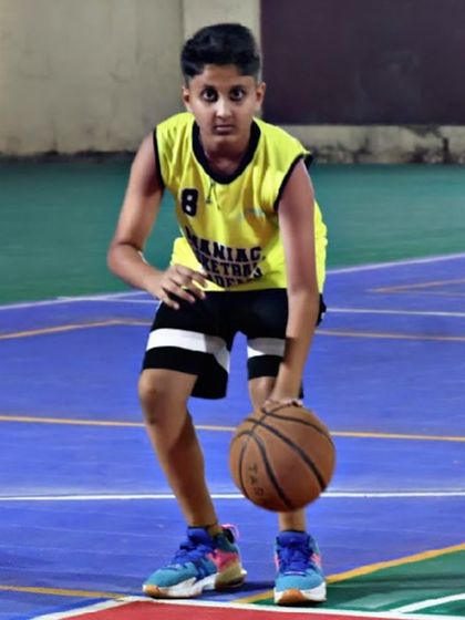 A young player practices his dribbling stance, keeping the ball low and controlled. This fundamental skill is the key to confident and effective ball handling on the court.