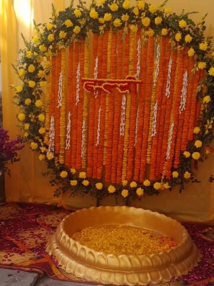 A classic Haldi setup with a large brass urli and a circular backdrop of orange and yellow marigolds. This is a timeless look for a traditional ceremony.