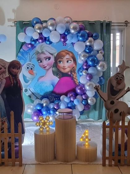 A compact and beautiful Frozen themed birthday setup for a home celebration, complete with character cutouts and a circular backdrop.