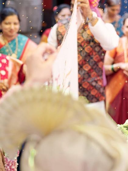 A close-up of the 'antarpat' ritual in a Maharashtrian wedding, where a cloth separates the couple before they see each other. This shot captures the anticipation and tradition of the moment.