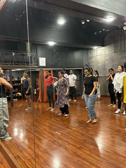 A mirror-view of the class, showing students learning and practicing together. The studio's mirrored walls are essential for self-correction and learning.