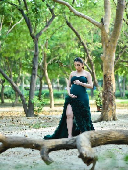 A solo portrait of an expectant mother in a lush green forest setting. The deep green of her gown complements the natural surroundings, creating a rich and vibrant pregnancy photograph.
