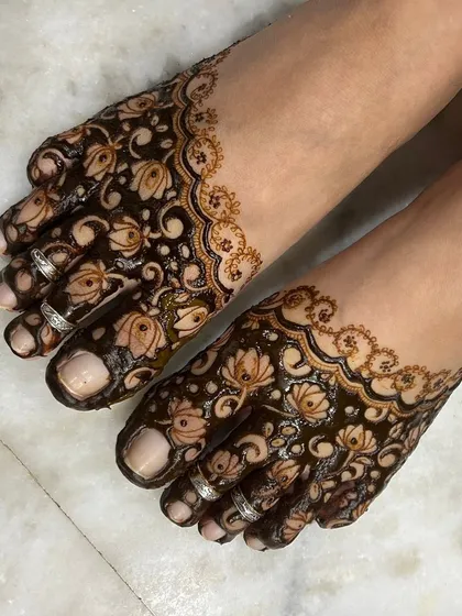 A matching baby shower mehandi design for the feet. The delicate floral patterns complement the designs on the hands, creating a complete and beautiful look for the mom to be.