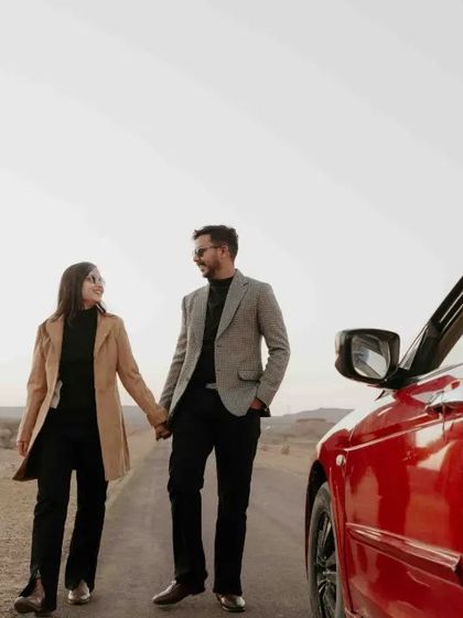 A close-up shot of the couple walking on the road, their happy expressions and the red car creating a perfect pre-wedding photo.