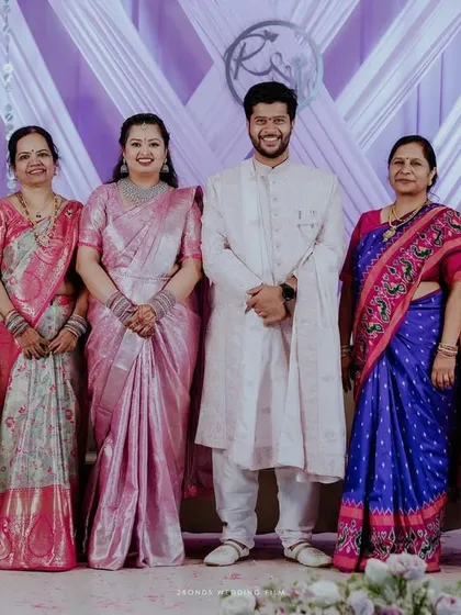 The happy couple with their family, posing for a group photo in front of the custom lavender backdrop we created for their engagement celebration.