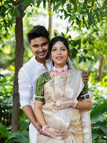 A classic portrait of the couple, smiling for the camera in a beautiful garden setting during their baby shower event.