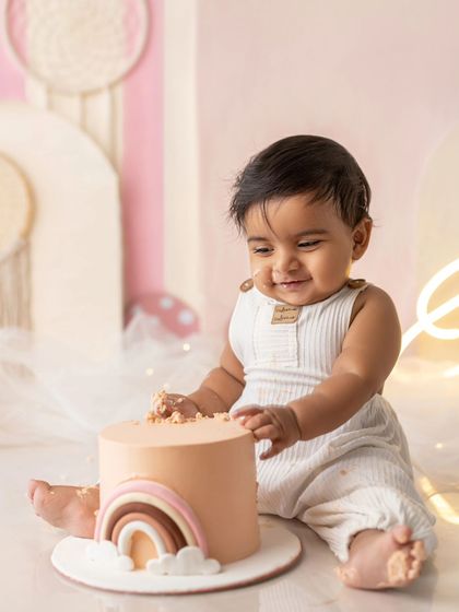 A happy baby boy enjoying his first taste of cake. The smile on his face is absolutely priceless.
