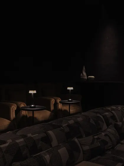 A glimpse into the dedicated home theatre at Rehethaan. We designed the space with curved, slatted walls and plush, tiered seating to create an immersive and luxurious cinematic experience for the family.