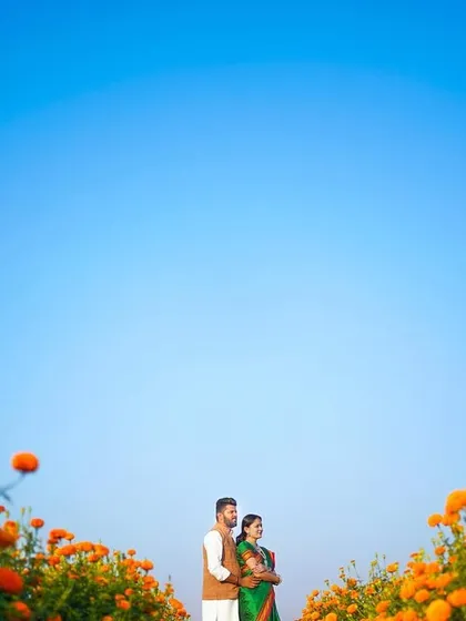 Using the vast blue sky and the vibrant orange of the marigold field to frame the couple. This wide-angle shot creates a sense of scale and beauty, making the couple the central focus in a breathtaking landscape.